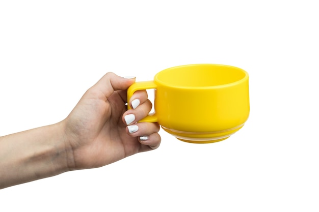 La main de la jeune fille avec une tasse de thé jaune isolé sur blanc. Main avec la vaisselle.