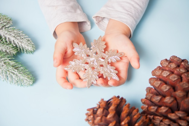 Main de jeune fille tenant un décor de Noël gros flocon de neige dans les mains