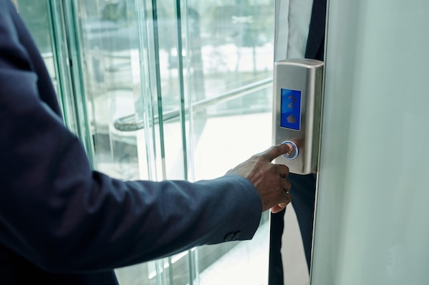 Main de jeune homme d'affaires afro-américain en appuyant sur le bouton d'appel sur le panneau