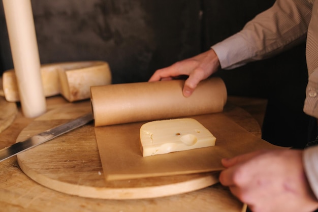 Main de jeune homme emballant une tranche de fromage