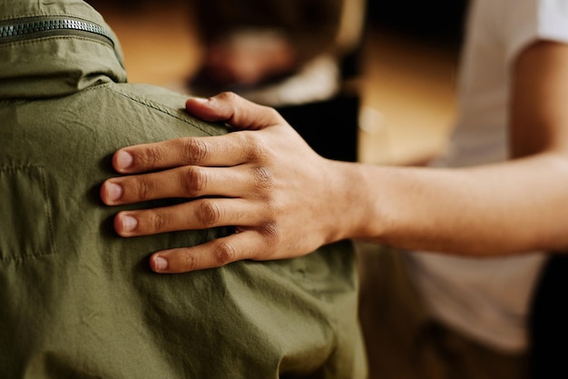 Main d'un jeune homme de soutien consolant son ami atteint du syndrome post-traumatique