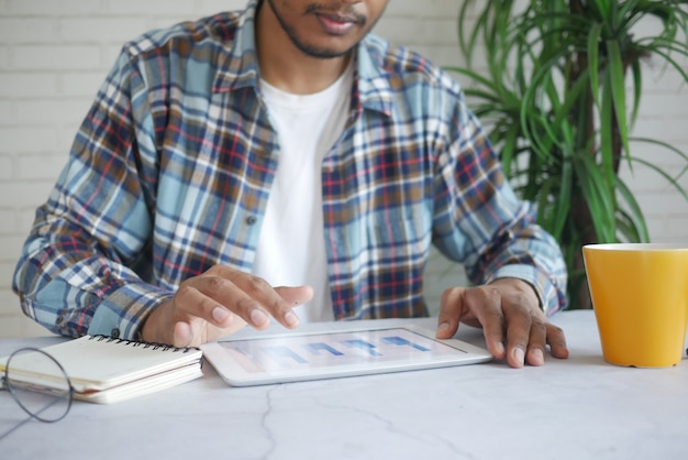 Main de jeune homme avec un stylo analysant un graphique à barres sur du papier blanc situé