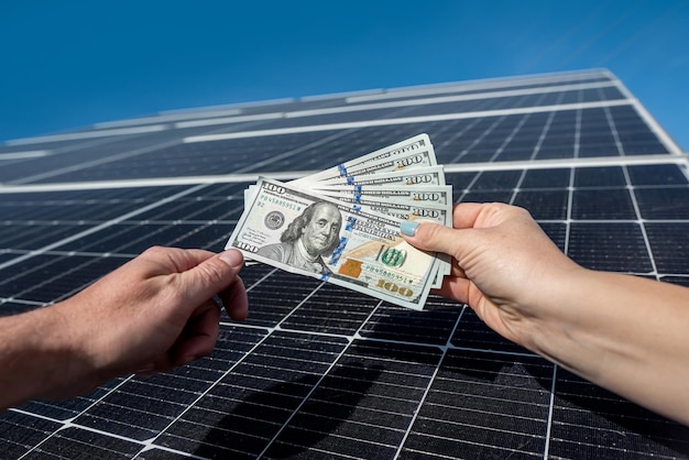 Main d'un jeune homme tenant des dollars et les remettant pour installer de nouveaux panneaux solaires Concept de paiement d'électricité verte du travail