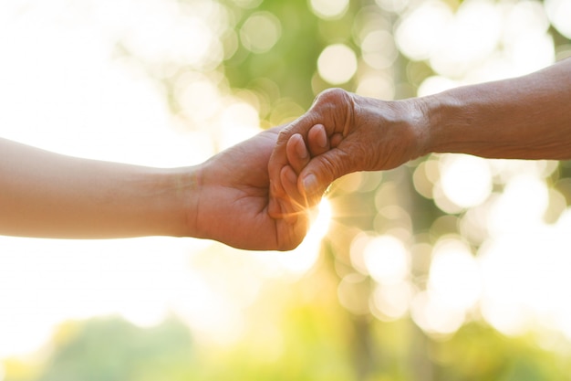 Main de jeune homme tenant la main d'une personne âgée