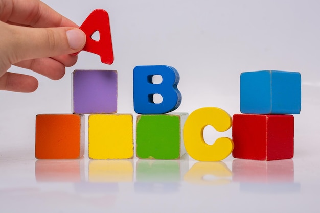 Main jouant avec des lettres de l'alphabet coloré et des blocs de construction