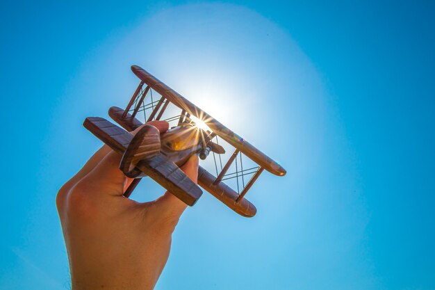 La main lance un avion en bois sur le fond du soleil