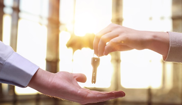 De main en main Gros plan de la main d'une vendeuse propriétaire d'un bureau d'appartement tenant les clés en la donnant à une jeune femme acheteuse locataire après la conclusion d'un accord réussi et l'obtention d'un acompte