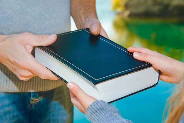 A De main en main, un parent passe un livre à un enfant dans un parc en plein air