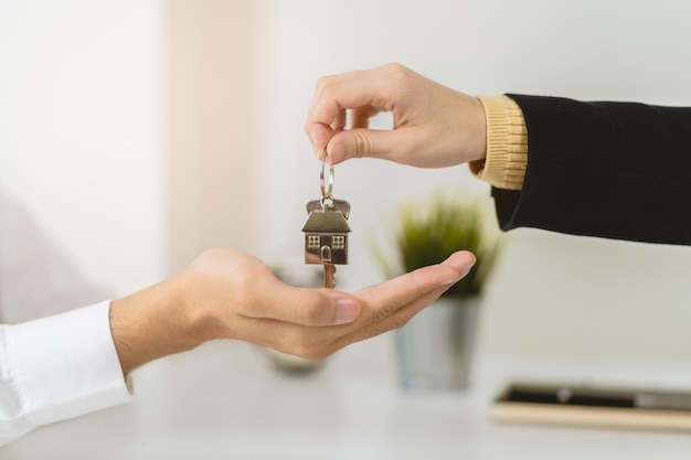 Photo main de maison, agent d'appartement ou agent immobilier détenant la clé donnant au jeune homme un nouveau propriétaire, locataire ou locataire. le banquier a approuvé l'achat avec signature signée. prêt hypothécaire, immobilier. propriété financière.