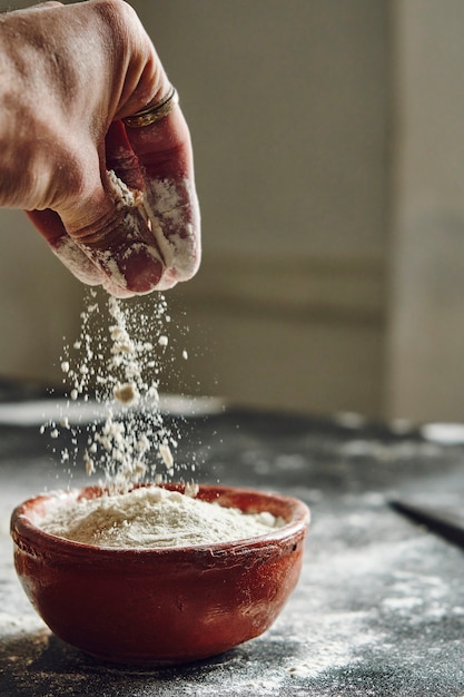 Main mâle prenant la farine d'un bol