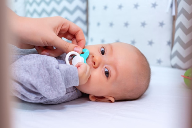 La main de maman donne une tétine au bébé. Mise au point sélective