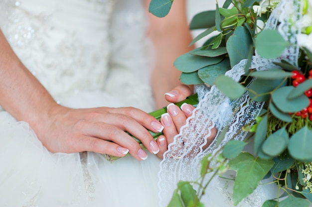 La main de la mariée avec une bague sur un gros plan de bouquet.