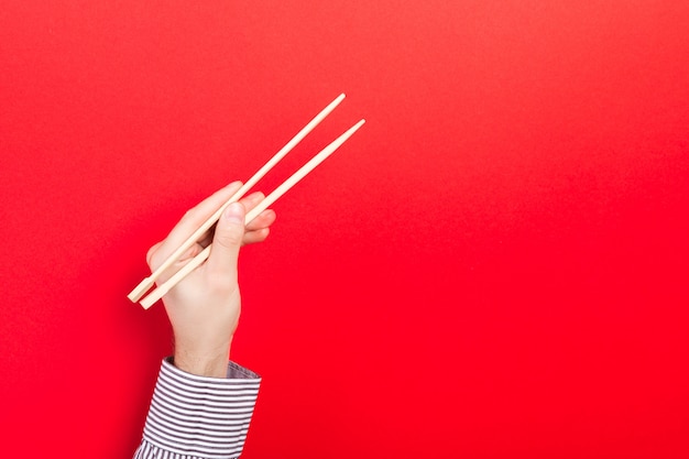 Main masculine avec des baguettes rouges. Cuisine asiatique traditionnelle avec emty