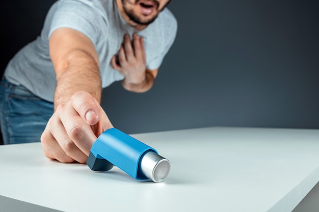 La main masculine cherche un inhalateur pour l'asthme, une crise d'asthme. Le concept de traitement de l'asthme bronchique, de la toux, des allergies, de la dyspnée.