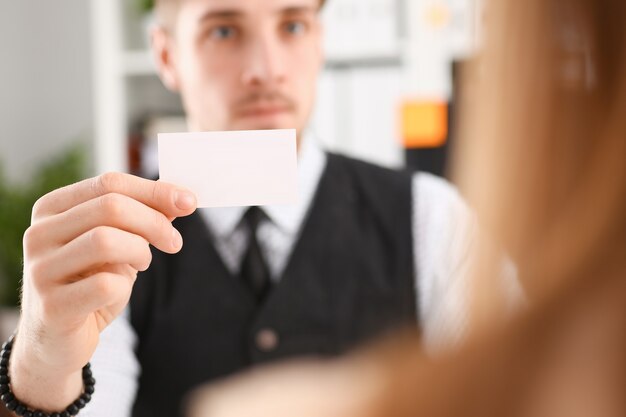 La main masculine en costume donne une carte de visite vierge au visiteur