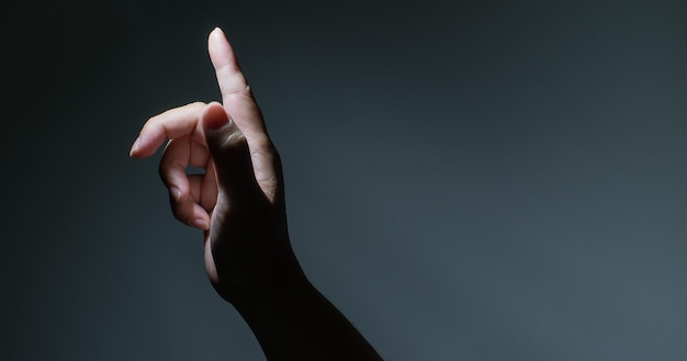 Photo main masculine avec le doigt pointé sur fond sombre