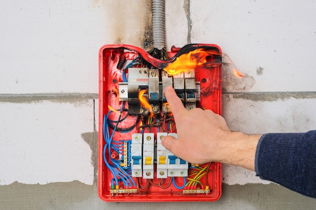 La main masculine éteint le tableau de distribution en cas de surcharge ou de court-circuit sur le mur