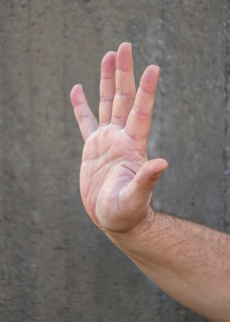 Main masculine sur fond gris monophonique dans un geste de bienvenue ou négatif