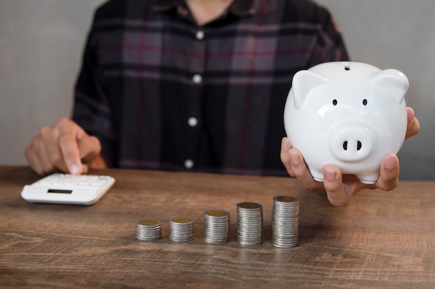 Photo main masculine mettant la pièce dans la tirelire pour économiser de l'argent et du concept financier