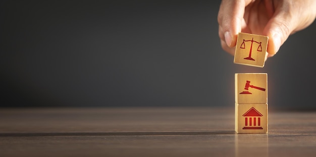 Main masculine montrant des cubes en bois avec des icônes loi justice juridique