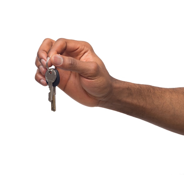 Main masculine noire tenant la clé de la maison, de la voiture ou de l'entreprise, affiche de motivation isolée sur fond blanc, espace de copie