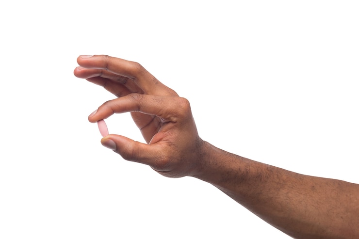 Photo main masculine noire tenant une pilule entre le pouce et l'index isolé sur fond blanc. soins de santé, concept de traitement
