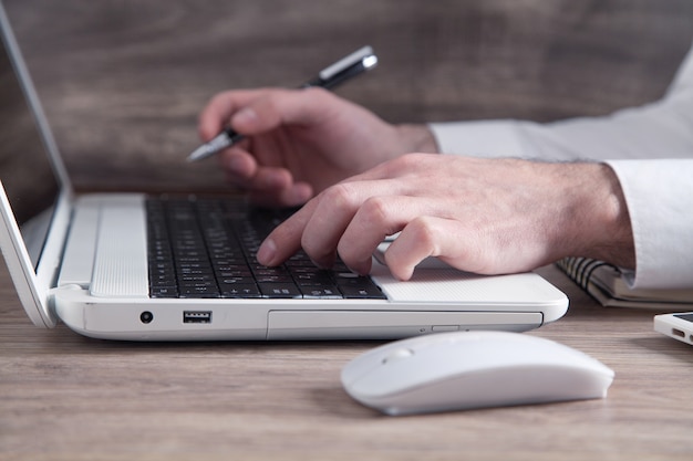 Main masculine tapant sur le clavier de l'ordinateur.