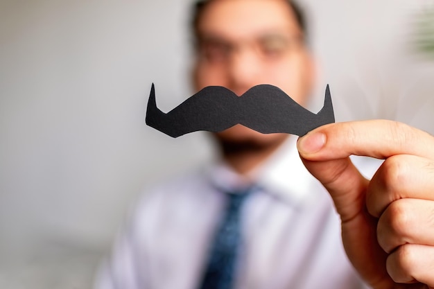 Main masculine tenant une moustache en papier concept Movember