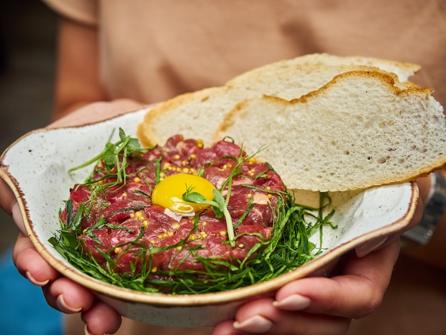 Photo la main masculine verse de l'huile d'olive sur un délicieux tartare de boeuf frais