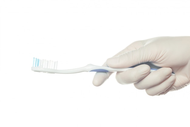 Main de médecin gantée tenant une brosse à dents