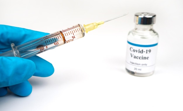 La main d'un médecin de sexe masculin porte un gant médical tenant une seringue et une bouteille de flacon avec un vaccin contre le virus corona covid 19