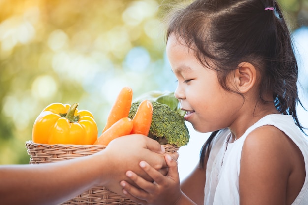 Main mère donnant un panier de légumes à la petite fille et elle le sentait