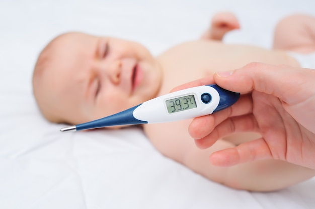 La main d'une mère ou d'un médecin tenant un thermomètre avec une marque de degrés