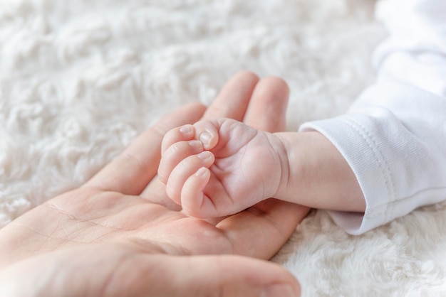 Main de mère tenant des doigts de bébé nouveau-né