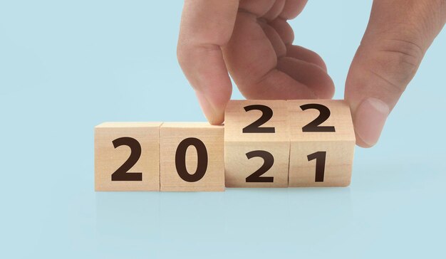 La main met un cube en bois avec la lettre du 2022 2021. cubes en bois debout dans la main