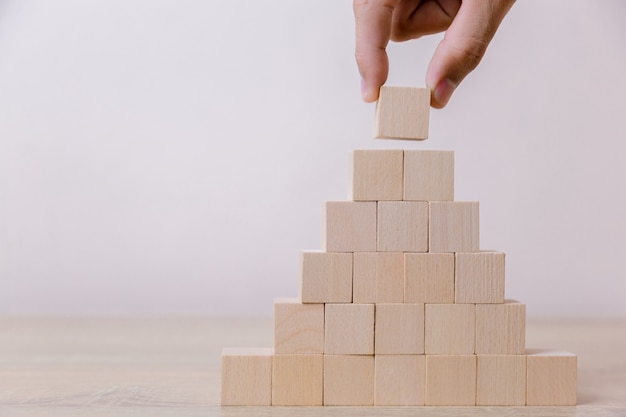 Main mettant des cubes en bois sur la pyramide supérieure.