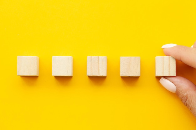 Main mettant et empilant des cubes en bois vierges sur la table