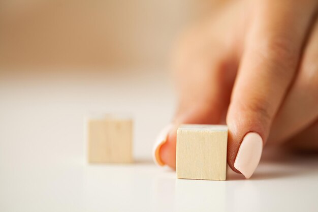 Main mettant et empilant des cubes en bois vierges sur la table