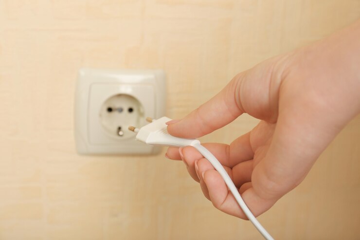 Photo main mettant la fiche dans la prise électrique