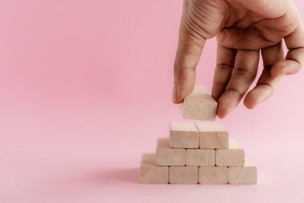 Main mettant le jouet en bois sur le mur rose