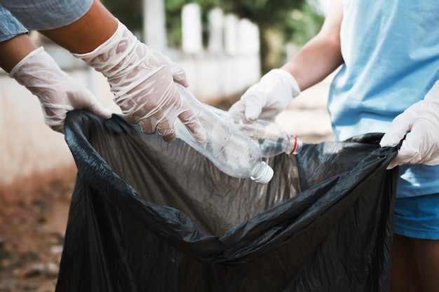 Main mettre une bouteille en plastique vide dans un sac poubelle noir