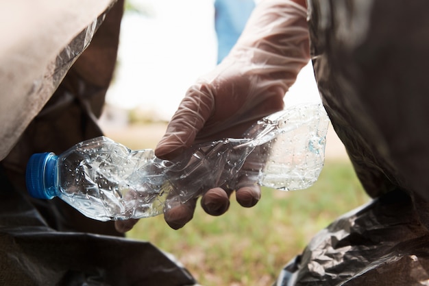 Main mettre une bouteille en plastique vide dans un sac poubelle noir