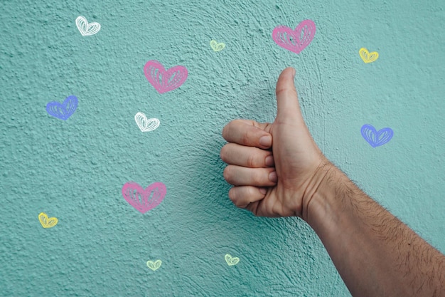 main sur le mur bleu avec des coeurs façonne la saint valentin