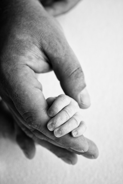 La main d'un nouveau-né endormi dans la main des parents mère et père gros plan Petits doigts d'un nouveau-né La famille se tient la main Macrophotographie en noir et blanc Concepts de famille et d'amour