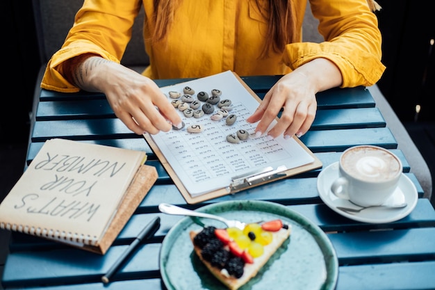 Photo main de numérologue féminine travaillant avec des tables de numérologie avec des nombres