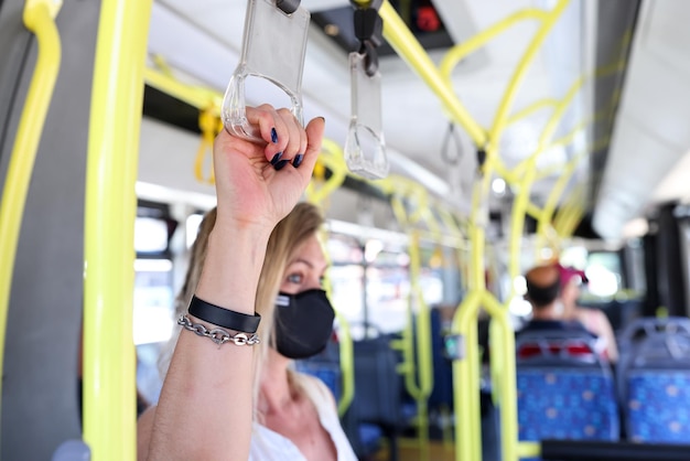 Main d'un passager touristique dans un masque de protection tenant des mains courantes dans la sécurité des bus en public