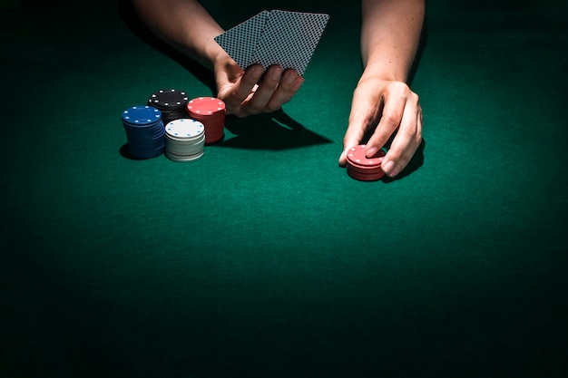 Main de personne jouant une carte de poker au casino