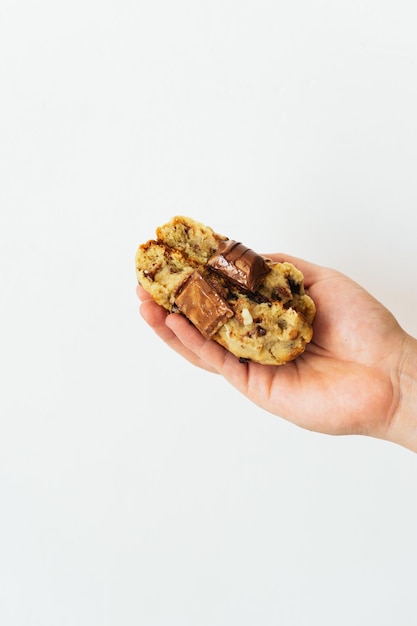 Photo main d'une personne méconnaissable tenant un cookie cassé avec du chocolat sur le dessus