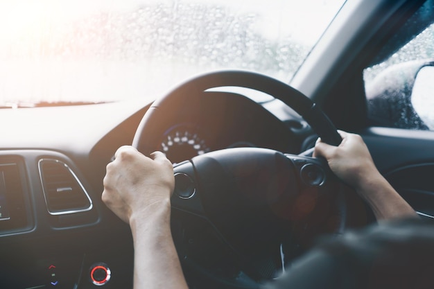 Main de personne sur le volant conduire une voiture avec fond de lumière du soleil.