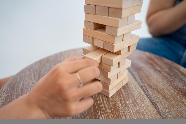 Main de personnes tenant un bloc tout en jouant à la tour de blocs